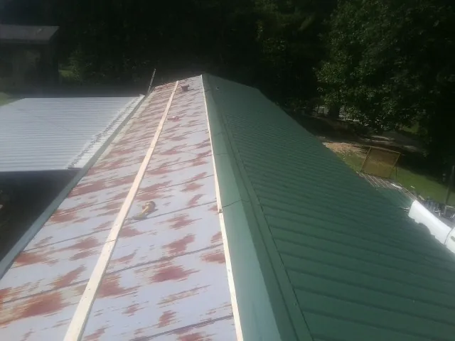 Old rusted panels beside newly installed green metal roofing — Wind Damage Roof Repair by Roofing Brothers in Lindon