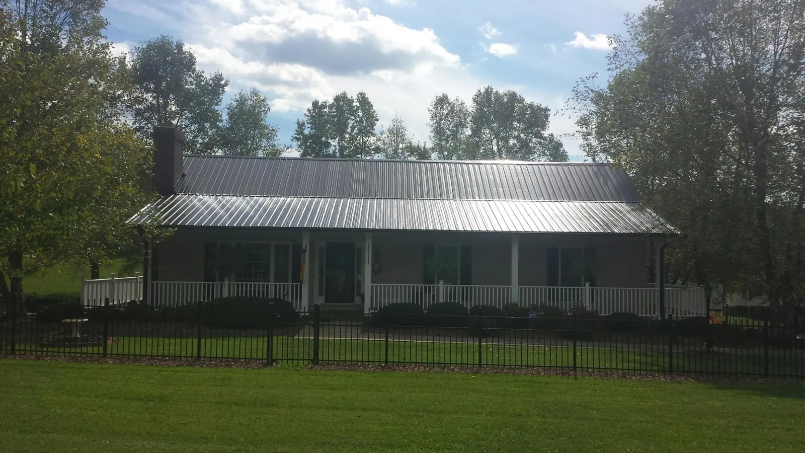 Gray metal roof on a brick ranch with a full width front porch — Gutter Guard Installation work by our crew in Lindon